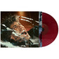 Red vinyl record partially removed from album sleeve featuring a man's face behind shattered glass