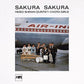 Jazz quintet and three women in kimonos posing with instruments in front of an Air India airplane