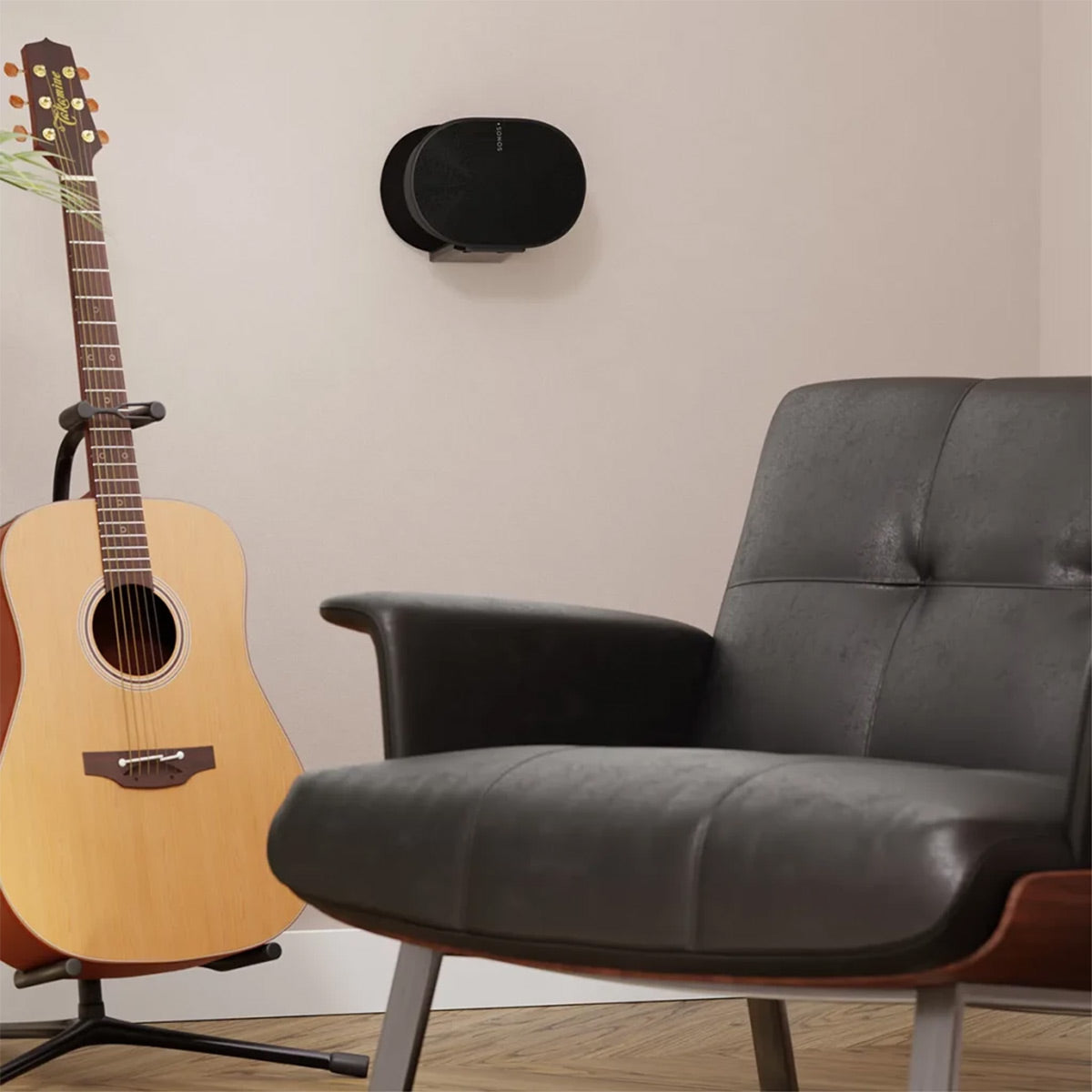 Black oval speaker mounted on a light wall above a leather chair