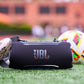 Black portable Bluetooth speaker with orange logo and top control buttons