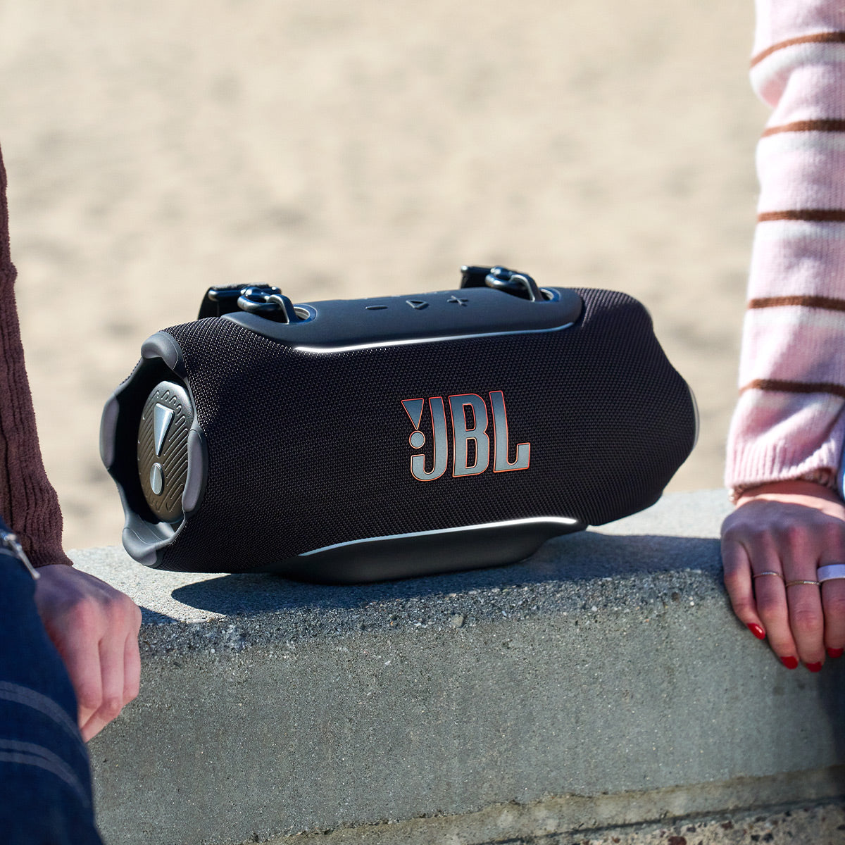 Black portable Bluetooth speaker with orange logo and top control buttons