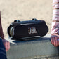 Black portable Bluetooth speaker with orange logo and top control buttons