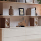 Pair of matte walnut bookshelf speakers with cream-colored drivers and gold accents